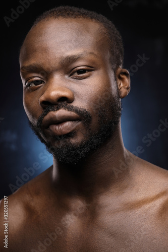 portrait of a handsome black man with naked sports torso looking in the camera on dark background
