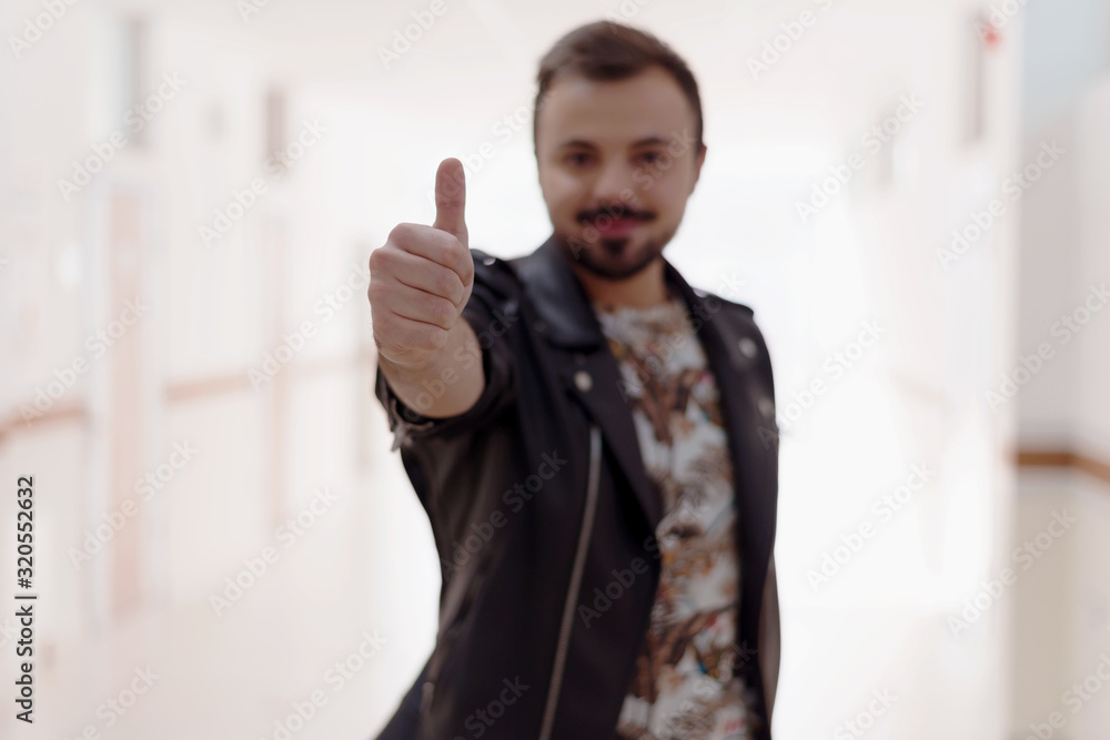 Portrait of smiling, bearded man gesturing thumb up in corridor or hall university. Concept approving, recommend, like new product. Portrait of smiling, bearded man gesturing thumb up in corridor or hall university. Concept approving, recommend, like new product.