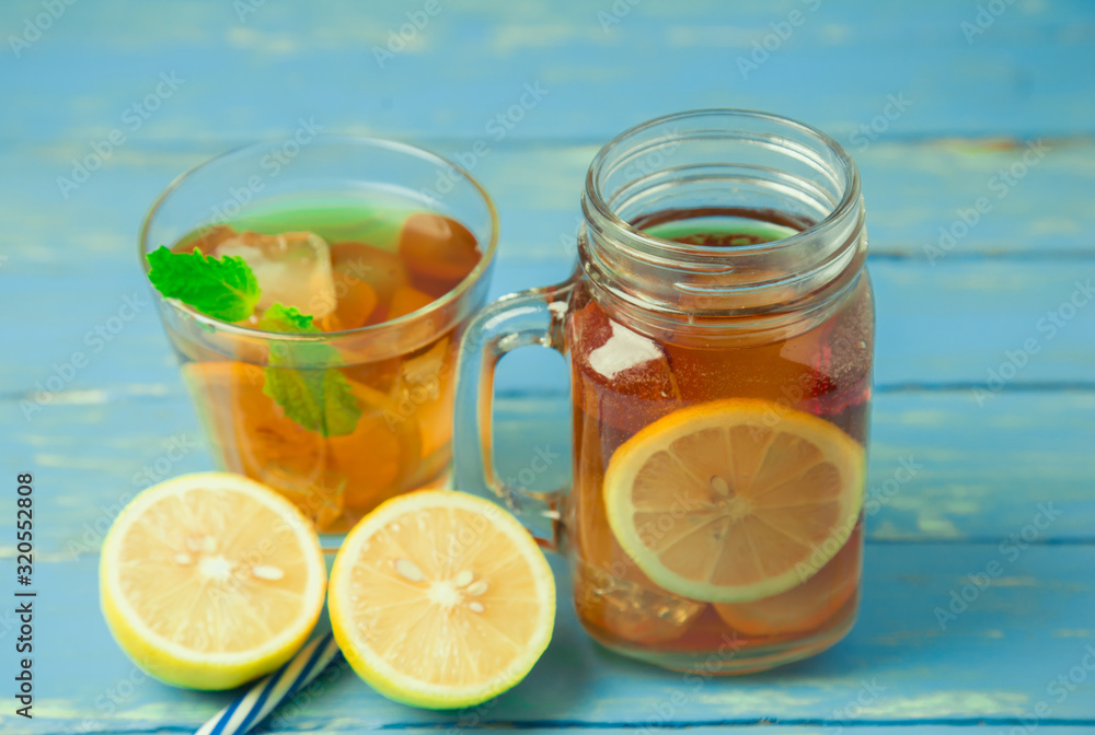 Iced tea with lemon slices and mint on wood background Iced tea with lemon slices and mint on wood background