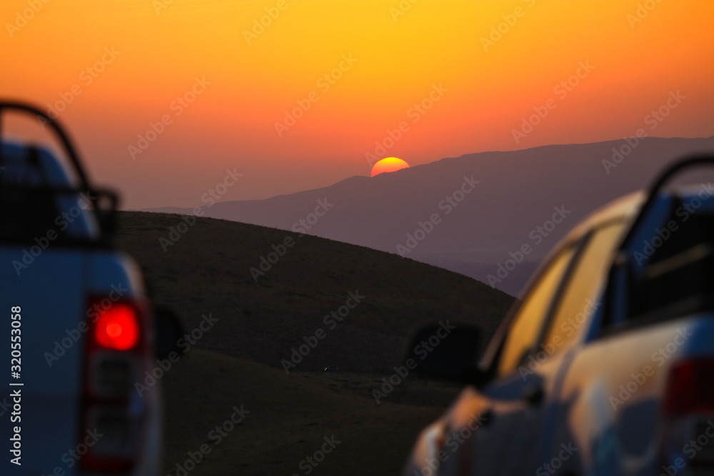 Silhouette of car on a background of a golden sunset in the mountains
