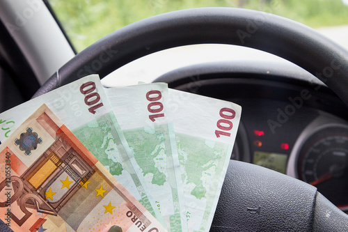 Euro banknotes of various denominations in a woman hand inside of a car