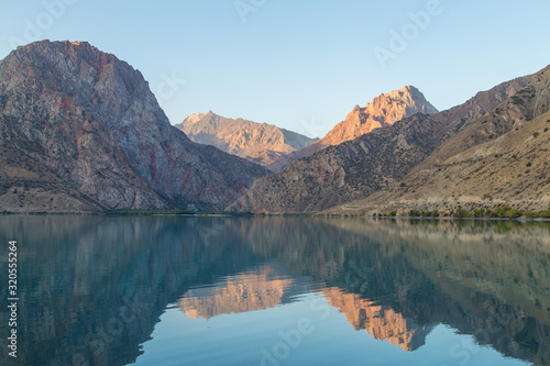 Mirror surface of Lake Iskanderkul at dawn amid the mountains