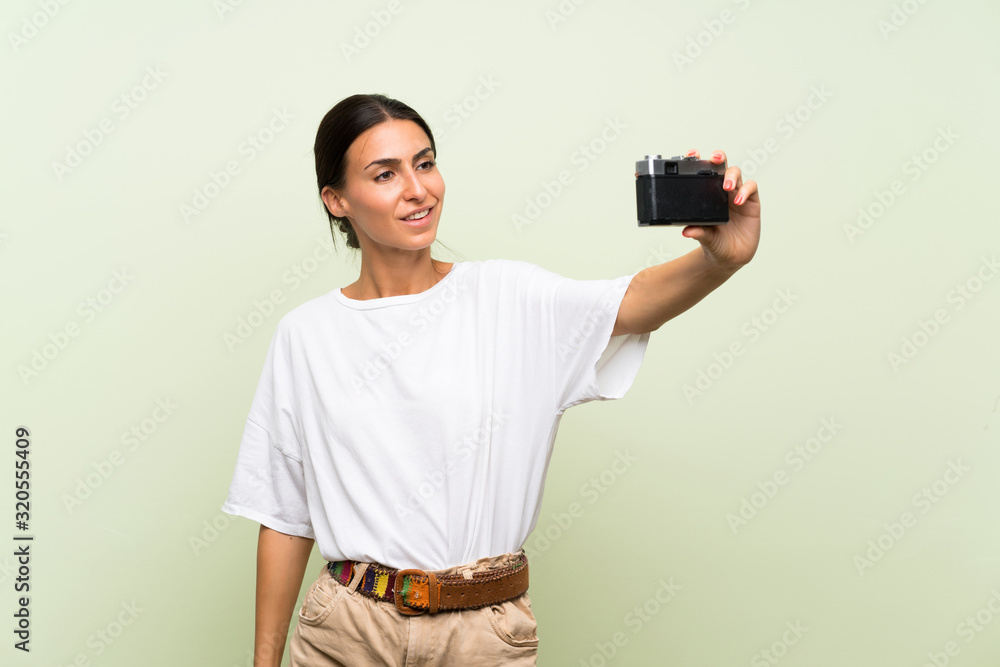Young woman over isolated green background making a selfie Young woman over isolated green background making a selfie