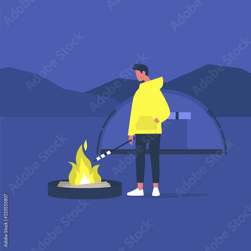 hiking in forest, young male tourist roasting marshmallows on a campfire,