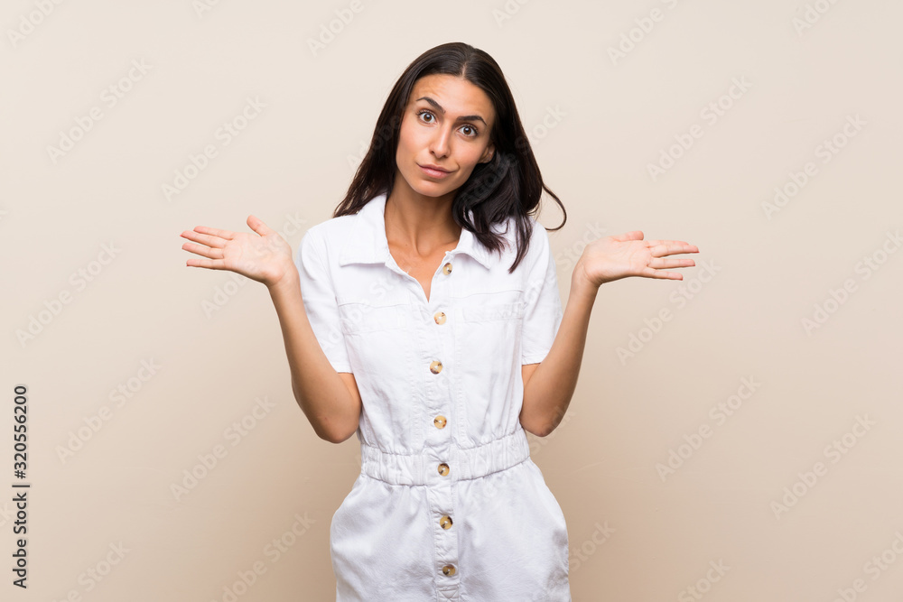 Young woman over isolated background having doubts while raising hands