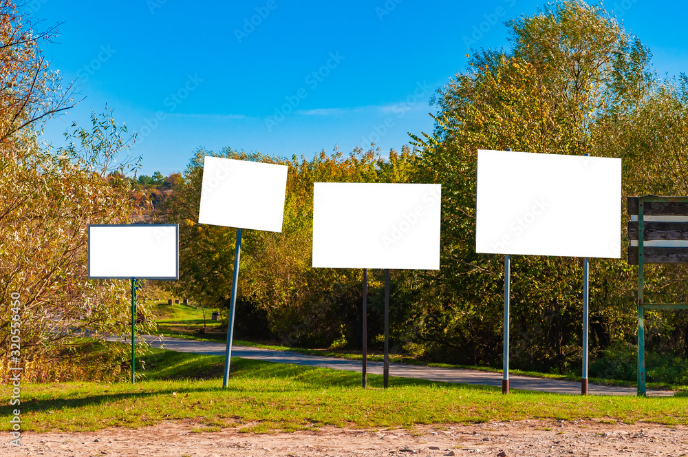 Blank white advertisement/annoucement board in the park. Sunny autumn day Blank white advertisement/annoucement board in the park. Sunny autumn day