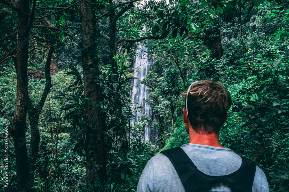 young man looking at a waterfall in the jungle in Tanzania Africa