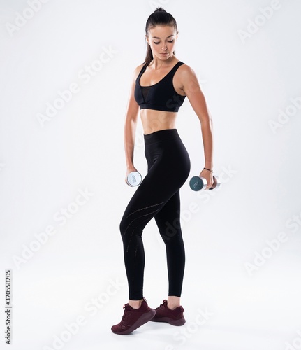 beautiful sporty muscular woman working out with two dumbbells