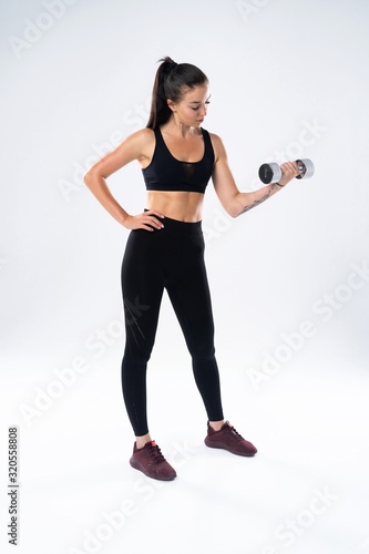 beautiful sporty muscular woman working out with two dumbbells