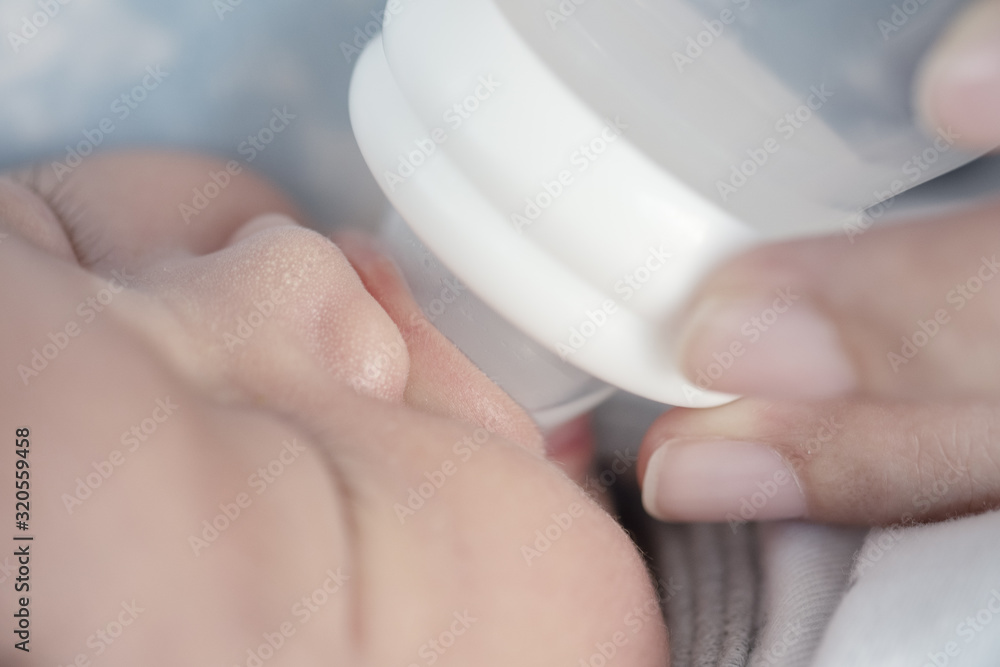 The child is sucking mother's milk from the bottle The child is sucking mother's milk from the bottle