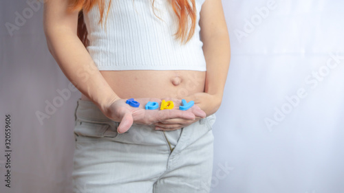 Pregnant woman is trying on her jeans or clothing that does not fit on her growing belly anymore in the first trimester