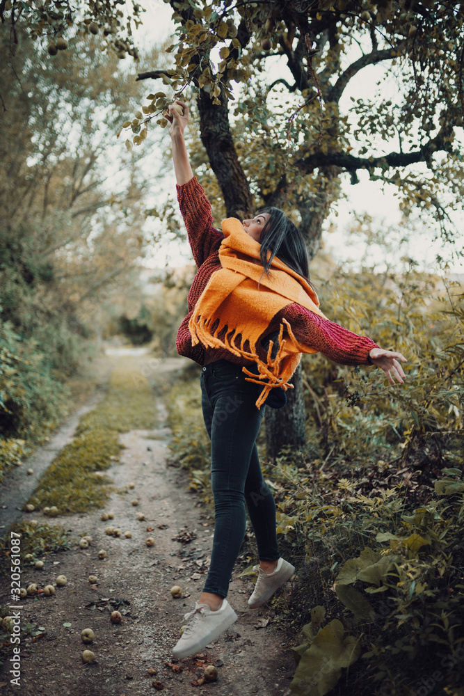 Young woman jumping to catch a pear from tree Young woman jumping to catch a pear from tree