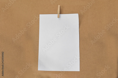 White paper and wood clip on brown paper background. © banphote