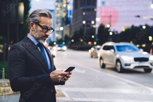 Adult businessman typing on smartphone against New York road © BullRun