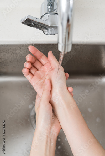 Asian woman washing hands in a sink