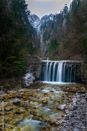 Waterfall in the forest with mountains in background