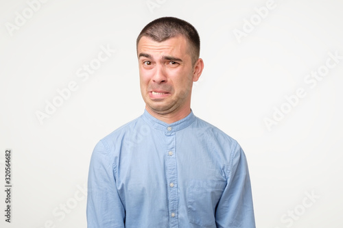 Funny young hispanic man showing cynical unhappy angry face