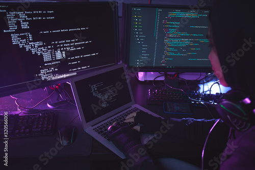 Murais de parede Unrecognizable young man surrounded by multiple screens programming or hacking s