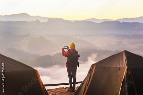 Hipster young girl with bright backpack taking photo of amazing landscape sunset on vintage camera on peak mountain mockup.
