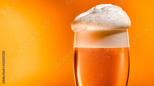 Quadro su tela Lager beer settles in the glass with a white cap of foam