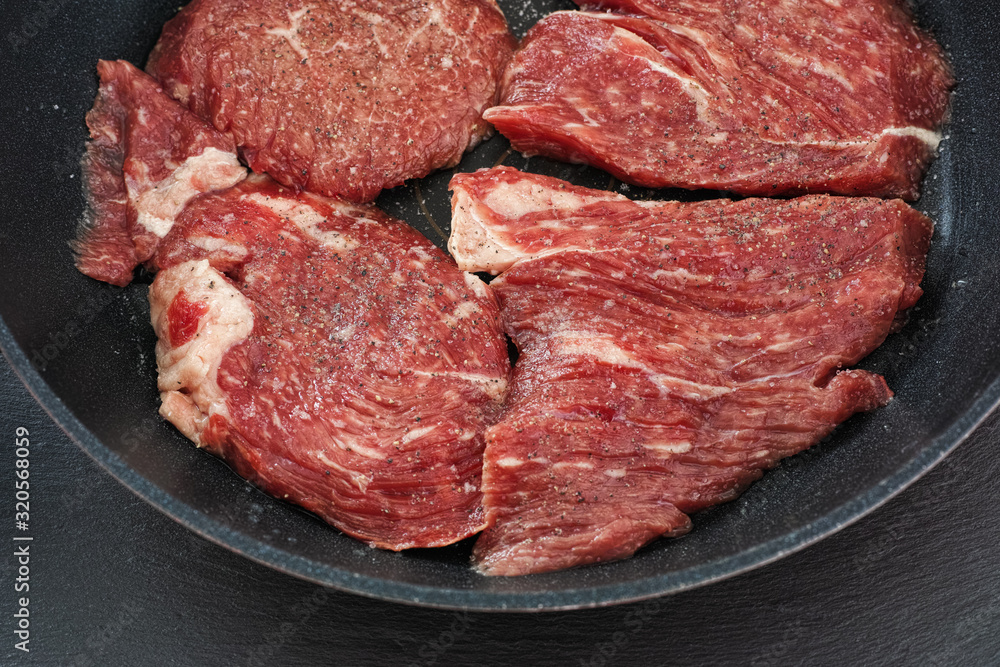 Fresh raw beef in a pan with black pepper and sea salt Fresh raw beef in a pan with black pepper and sea salt