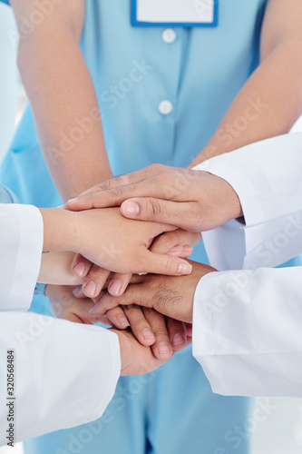 Close-up image of healthcare workers stacking hands to support each other befor long day of work