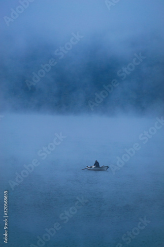 A fisherman in the morning mist on a lake