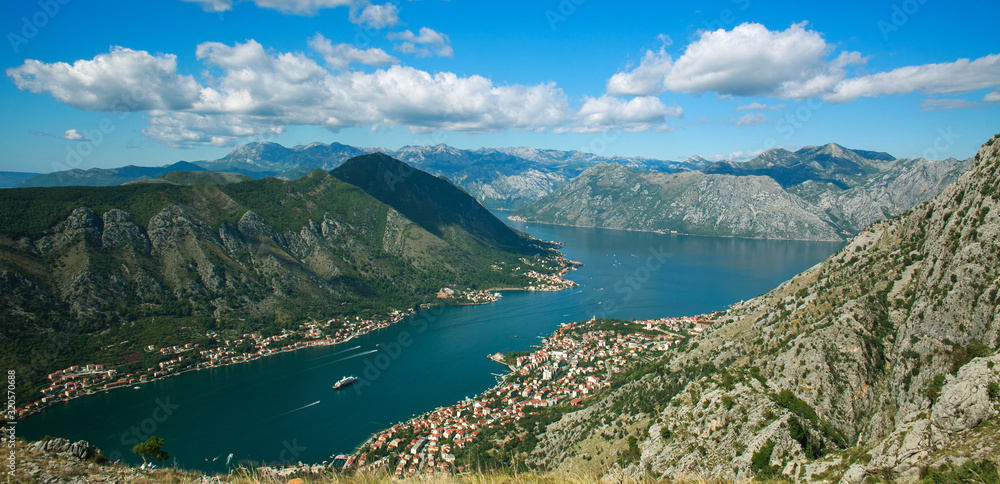 Top view of Kotor bay and old town surrounded by rocks of mountains on blue sky Top view of Kotor bay and old town surrounded by rocks of mountains on blue sky