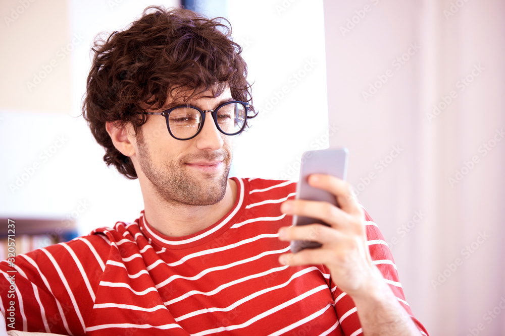 Portait of happy young man text messaging while sitting on sofa at home Portait of happy young man text messaging while sitting on sofa at home