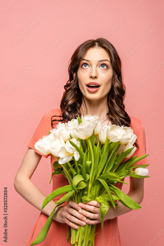 surprised girl looking up while holding bouquet of white tulips isolated on pink surprised girl looking up while holding bouquet of white tulips isolated on pink