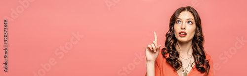 panoramic shot of thoughtful young woman showing idea gesture while looking up isolated on pink