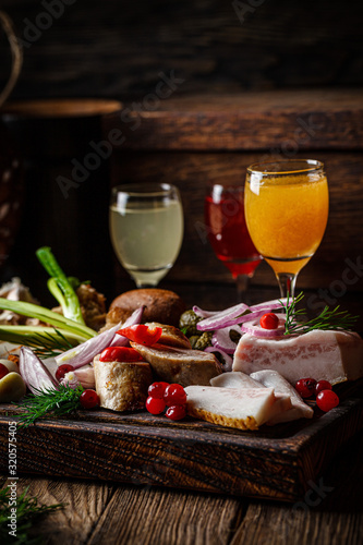 European cuisine in Ukrainian style. Meat set of homemade sausage, lard and bread. Serving dishes in a restaurant on wooden board with alcoholic drinks. background image copy space
