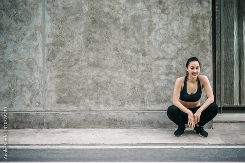 Young Asian woman athlete sitting and smiling after exercising to revitalize