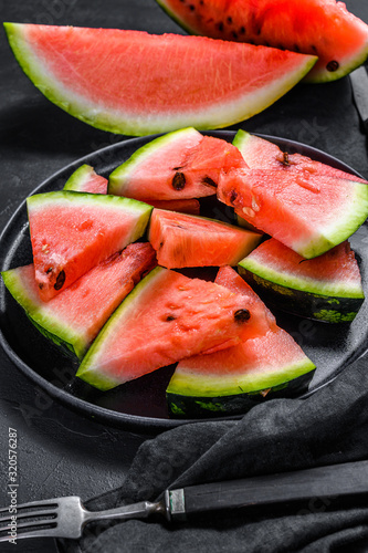 Slices of ripe watermelon in a plate on a dark background. Selective focus.