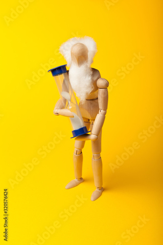 Figure of old man holds hourglass as a concept of old age and approach of death.