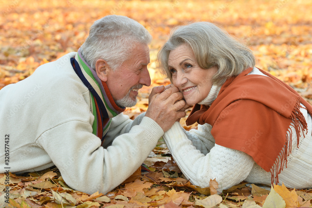 Happy senior couple lying on autumn leaves Happy senior couple lying on autumn leaves