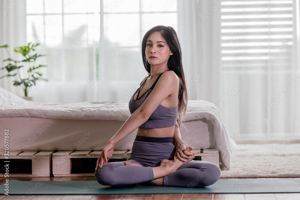 Attractive Asian woman practice yoga Seated Twist pose to meditation in bedroom after wake up in the morning Feeling so comfortable and relax,Healthcare Concept Attractive Asian woman practice yoga Seated Twist pose to meditation in bedroom after wake up in the morning Feeling so comfortable and relax,Healthcare Concept
