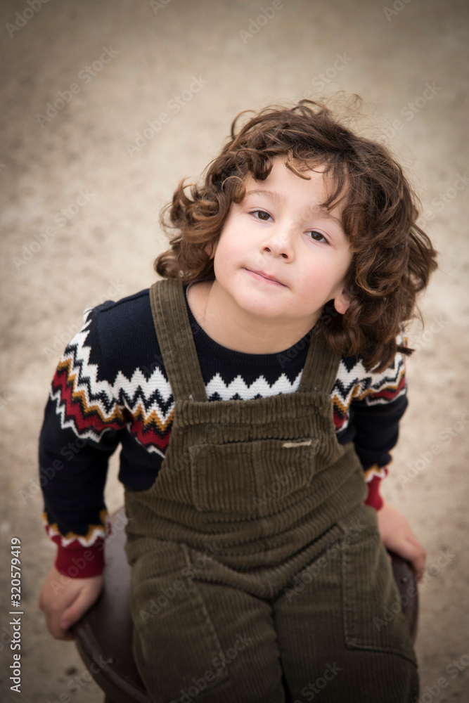 little boy with curly hair and without a tooth posing with a green bib little boy with curly hair and without a tooth posing with a green bib