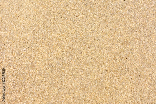 Golden sand background with selective focus. Textured yellow sand surface with soft focus. Summertime. Beach vacation. Seascape with clean sand. 