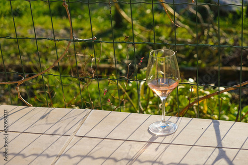 Glass of rose wine on the sun terrace table. Rural landscape in Provence.