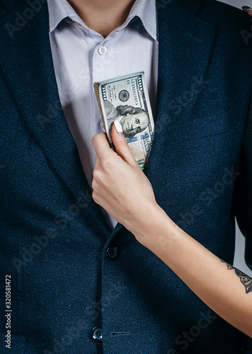 A girl takes money out of a jacket pocket of a male businessman