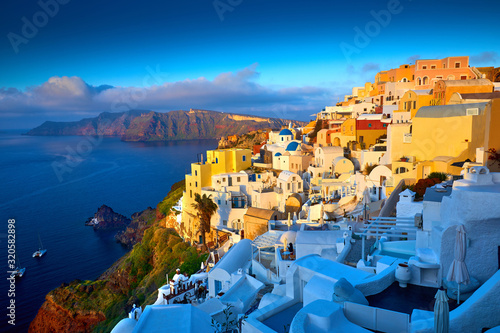 Oia town on Santorini island, Greece. Traditional famous houses and churches with blue domes over the Caldera, Aegean sea. Oia village in the morning light. Amazing sunrise view with white houses.