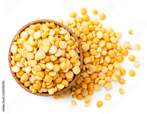 Fototapeta Yellow peas in a wooden plate and scattered on a white