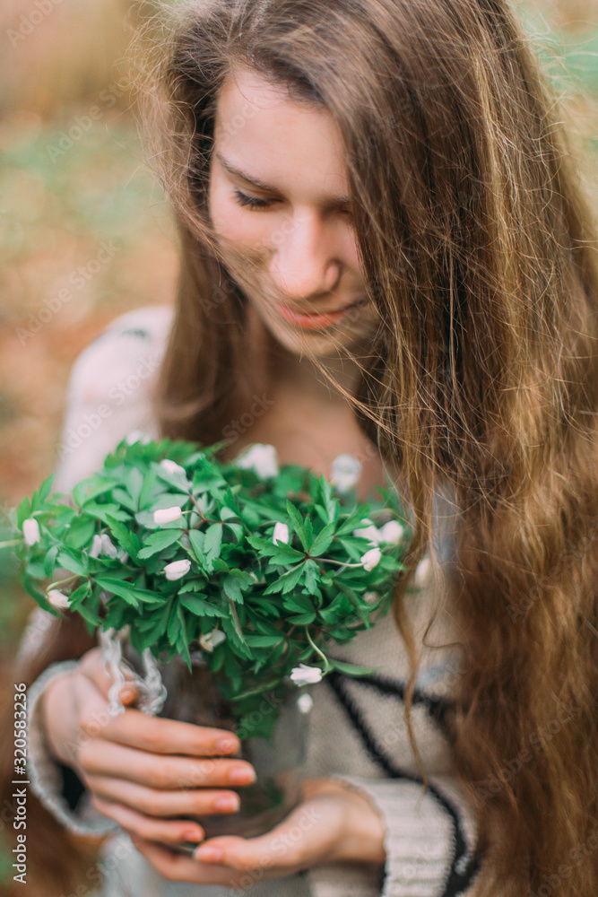 pretty girl holding white spring flowers walking through the green forest pretty girl holding white spring flowers walking through the green forest