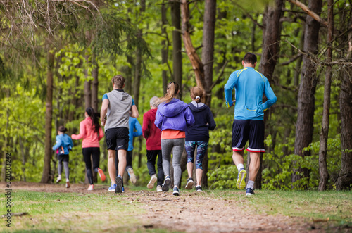 Rear view of large group of multi generation people running in nature.
