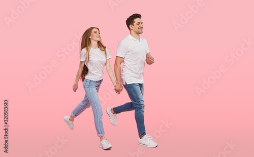 Happy couple walking together on pink background