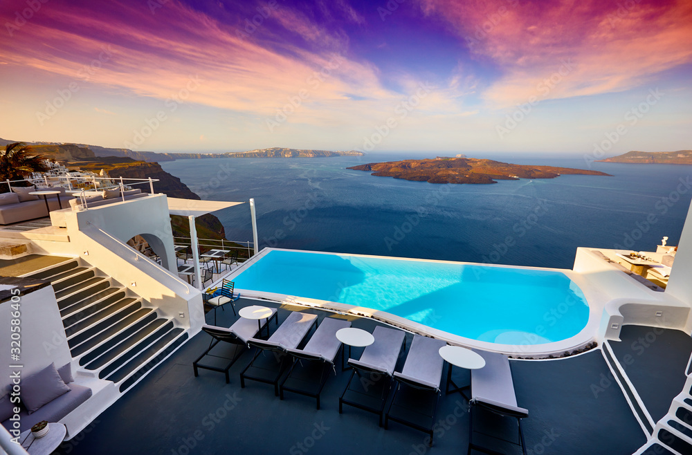 Swimming pool on the hotel terrace of fira's town on Santorini island, Greece. Incredibly romantic sunset on Santorini. Oia village in the morning light. Amazing sunset view with white houses.