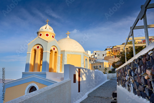 Fira town on Santorini island, Greece. Famous houses and churches and monastery over the Caldera, Aegean sea. Oia village in the morning light. Amazing sunrise view on Santorini's street