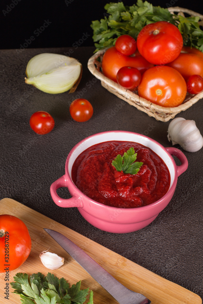 Tomato soup with parsley, onion and garlic on gray background. Comfortable food. Rustic style.. Tomato soup with parsley, onion and garlic on gray background. Comfortable food. Rustic style..