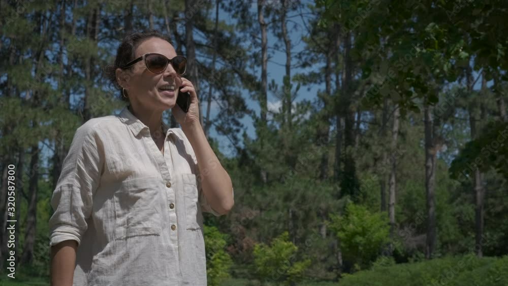In the woods with a phone. Cute woman talking on the phone in the summer outdoors. In the woods with a phone. Cute woman talking on the phone in the summer outdoors.